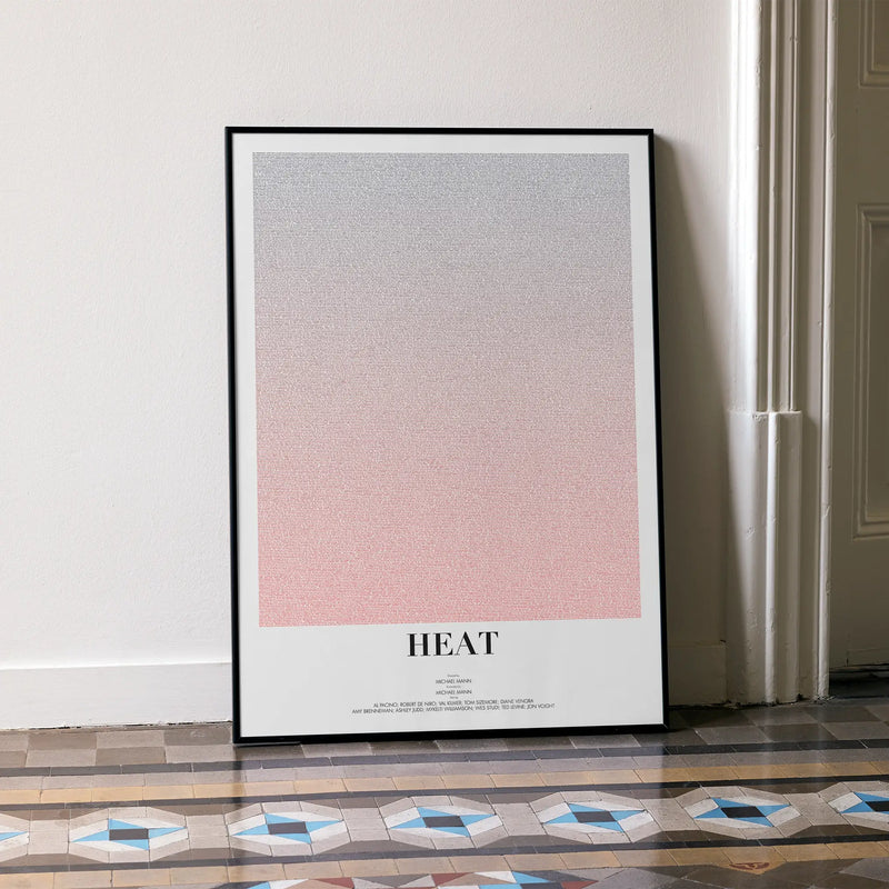 A framed Heat movie script poster leaning against a wall in a minimalist interior.