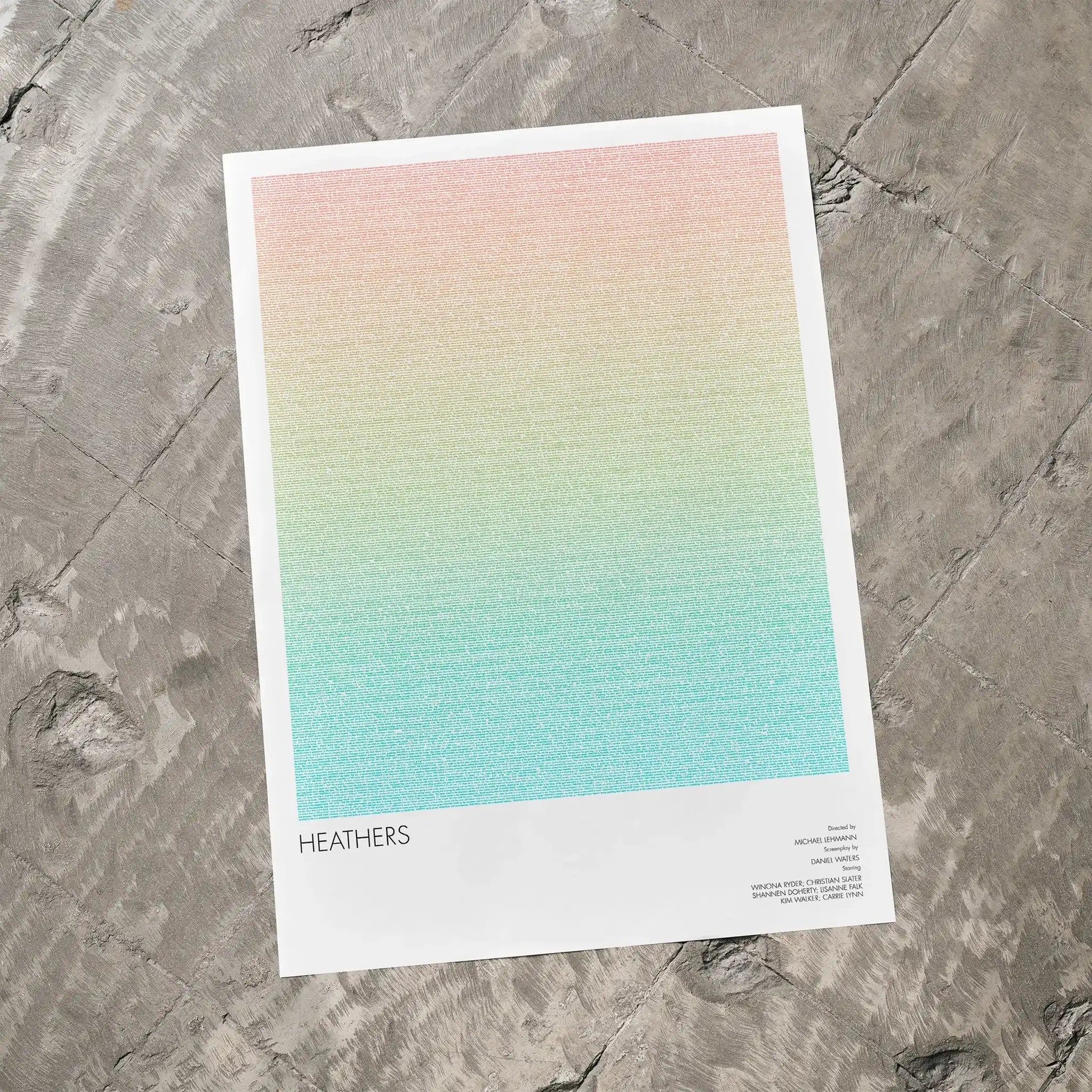 A Heathers movie script poster laid flat on a textured floor surface.