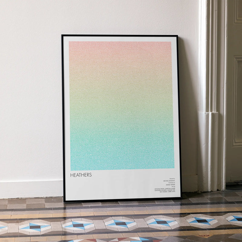 A framed Heathers movie script poster leaning against a wall in a minimalist interior.