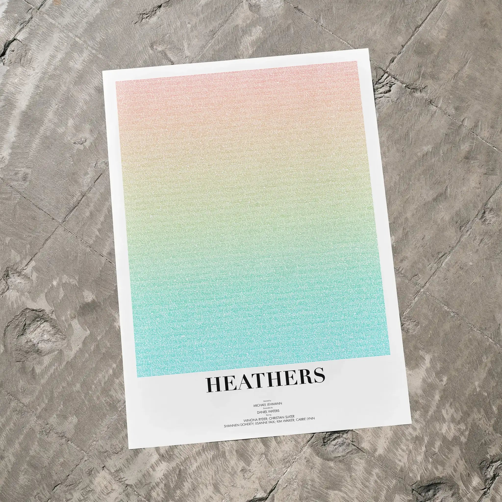 A Heathers movie script poster laid flat on a textured floor surface.