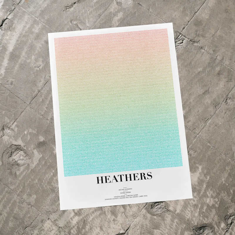 A Heathers movie script poster laid flat on a textured floor surface.