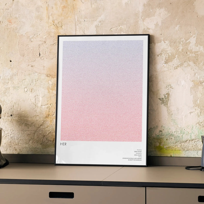 A framed Her movie script poster displayed on a cabinet in a minimalist interior.