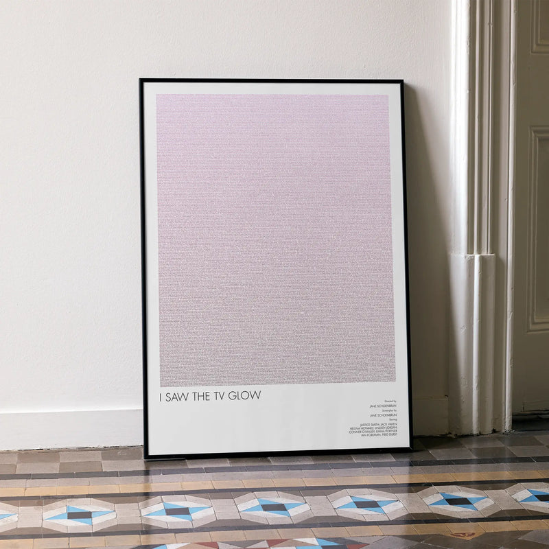A framed I Saw the TV Glow movie script poster leaning against a wall in a minimalist interior.