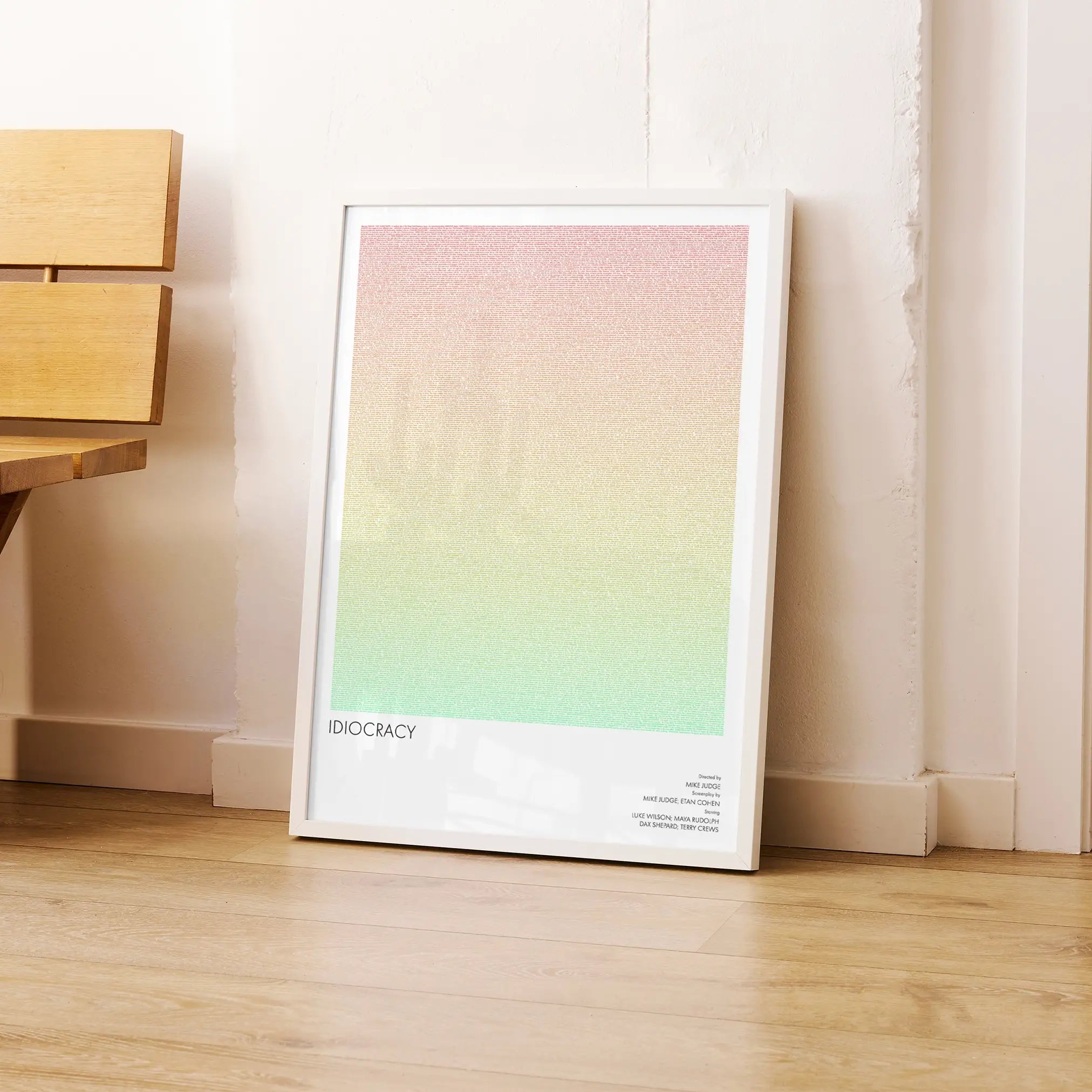 A framed Idiocracy movie script poster leaning against a wall in a modern interior.