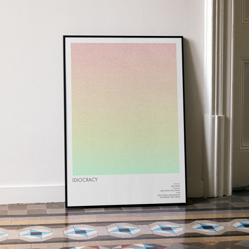 A framed Idiocracy movie script poster leaning against a wall in a minimalist interior.