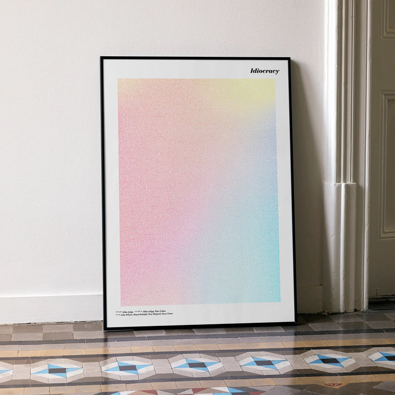 A framed Idiocracy movie script poster leaning against a wall in a minimalist interior.