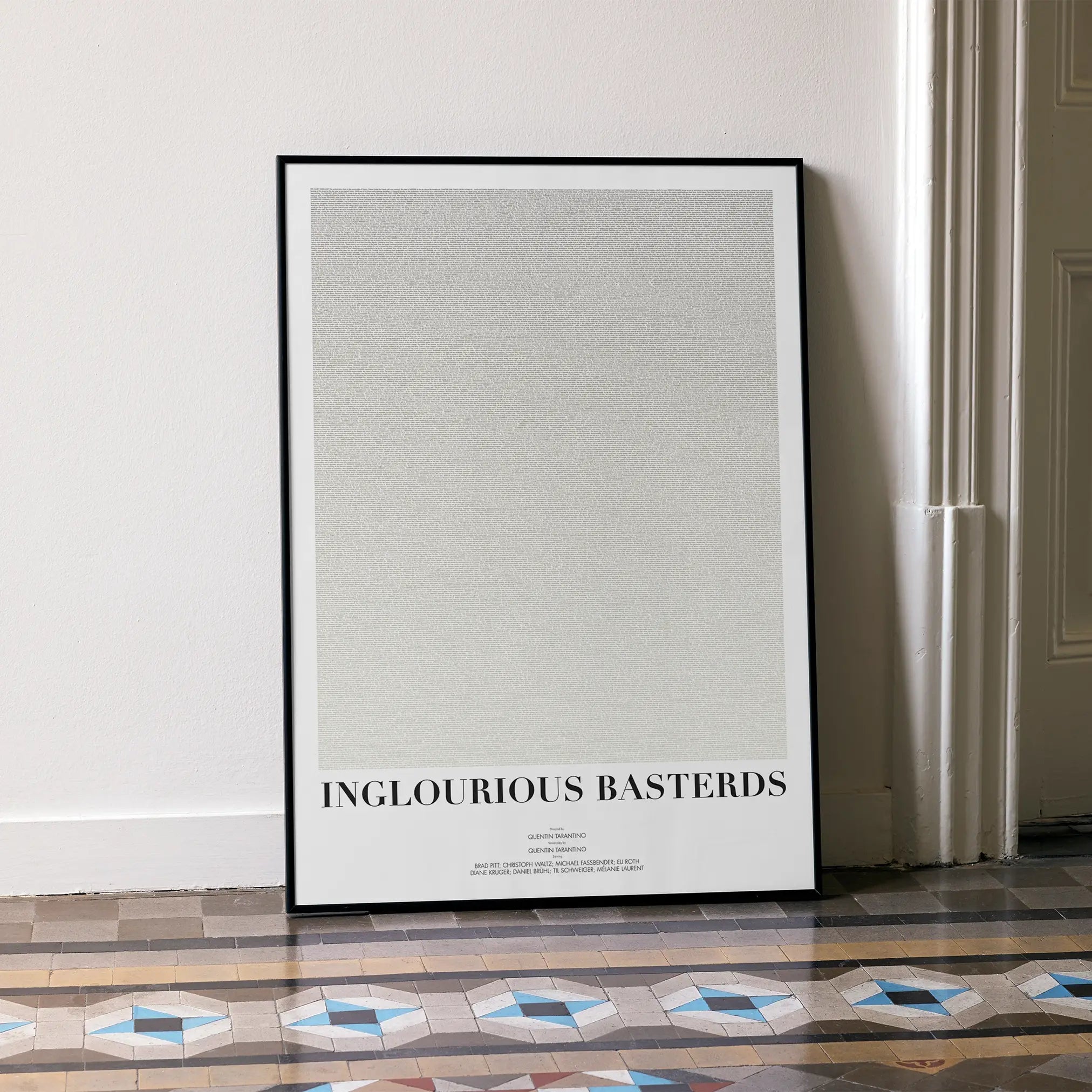 A framed Inglourious Basterds movie script poster leaning against a wall in a minimalist interior.