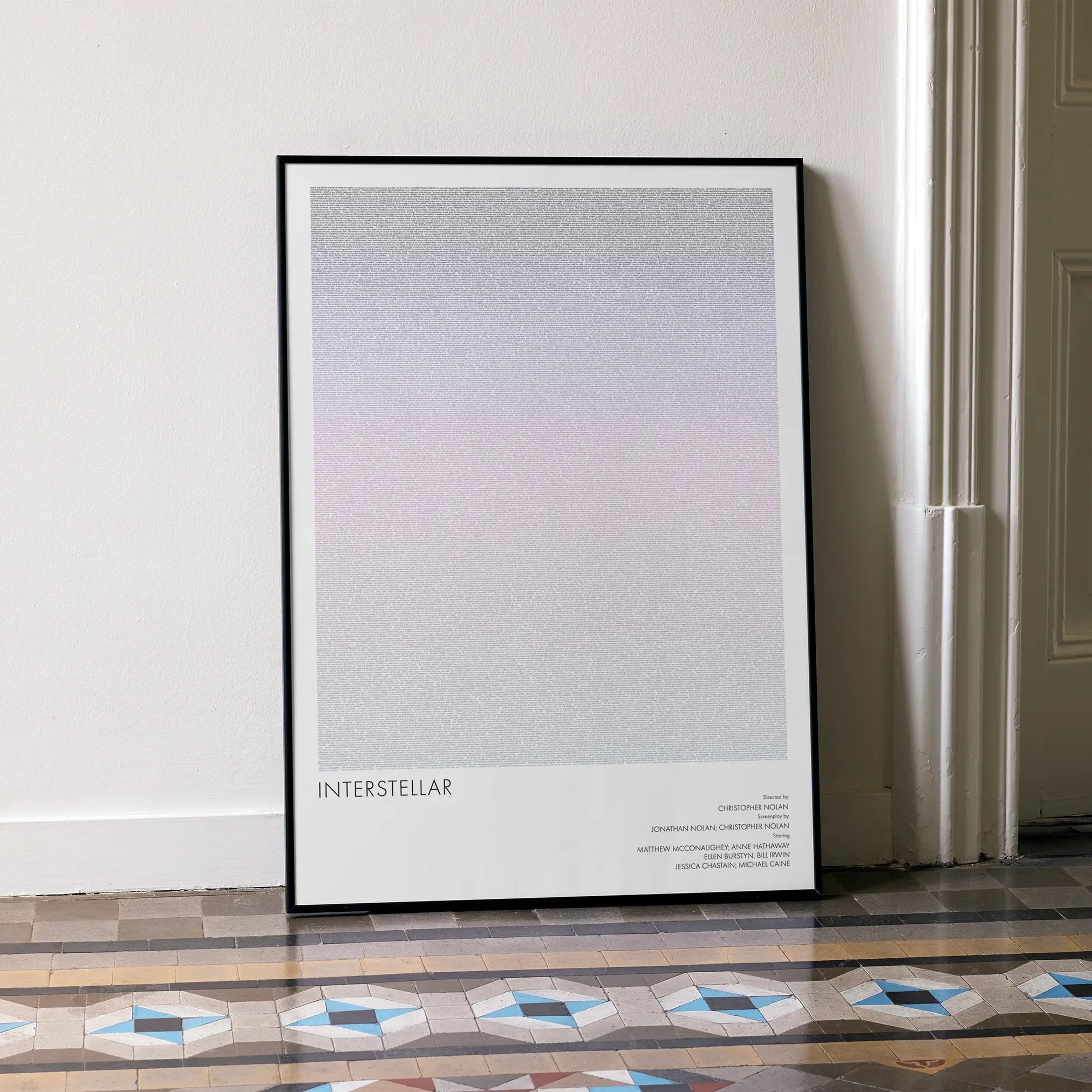 A framed Interstellar movie script poster leaning against a wall in a minimalist interior.