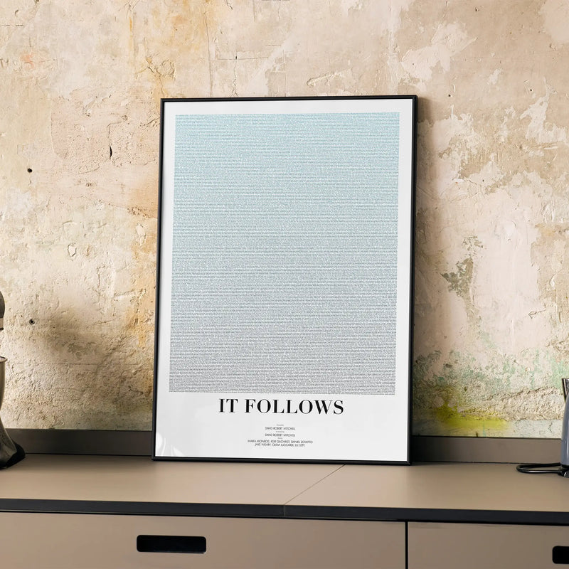 A framed It Follows movie script poster displayed on a cabinet in a minimalist interior.