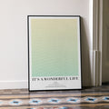 A framed It's a Wonderful Life movie script poster leaning against a wall in a minimalist interior.