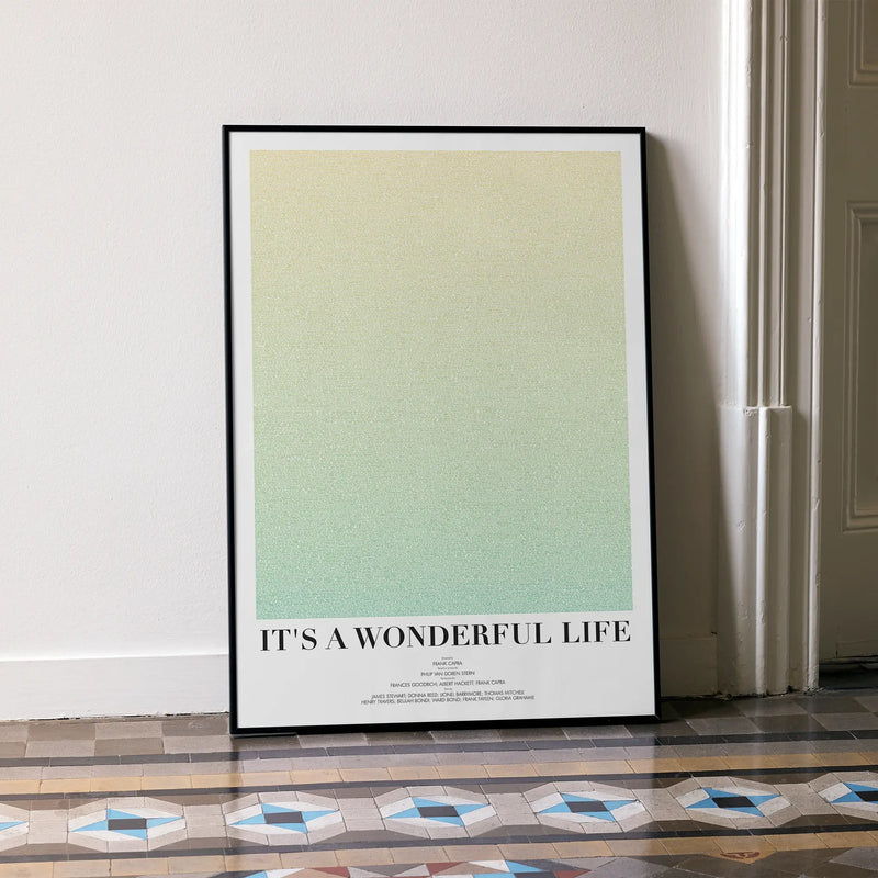 A framed It's a Wonderful Life movie script poster leaning against a wall in a minimalist interior.