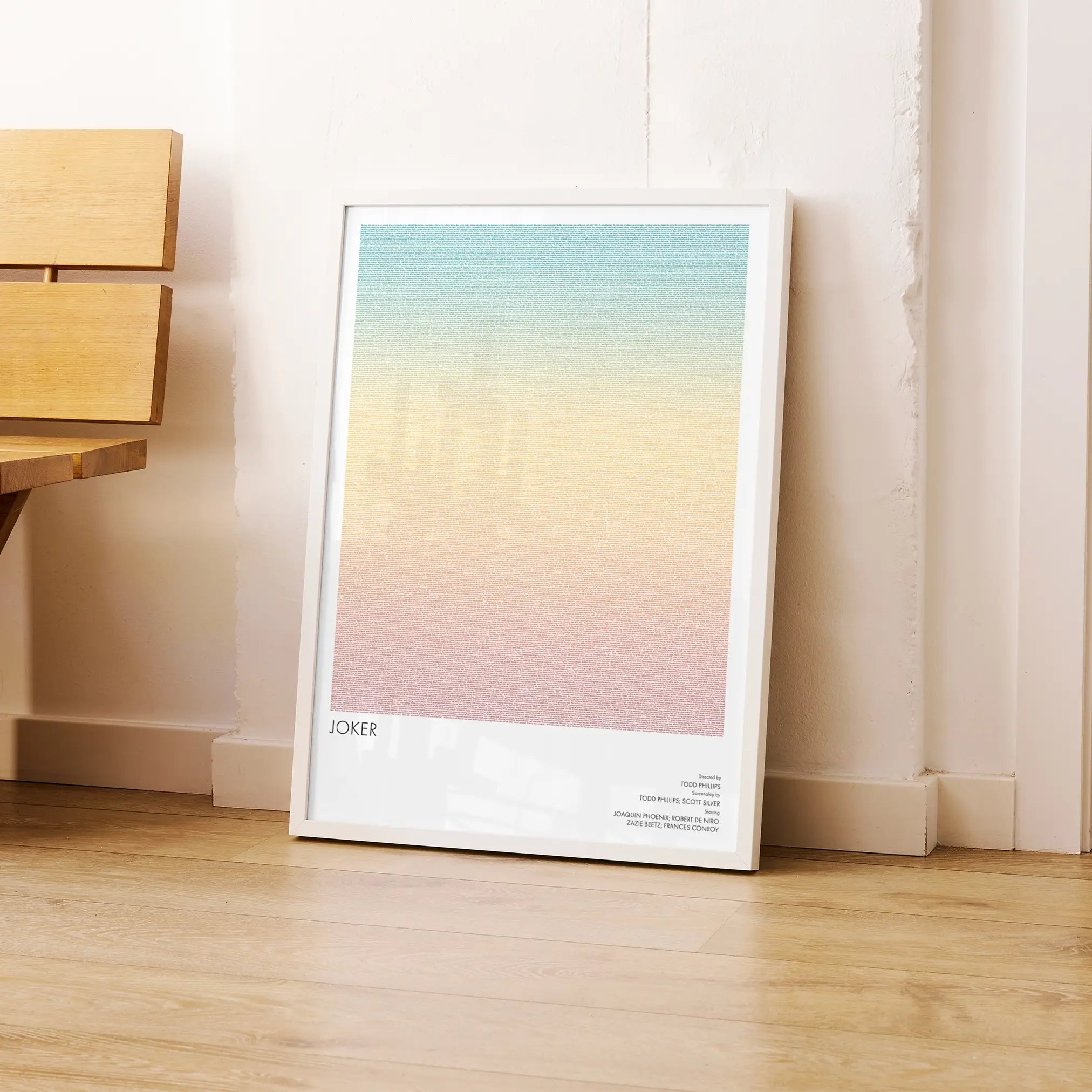 A framed Joker movie script poster leaning against a wall in a modern interior.