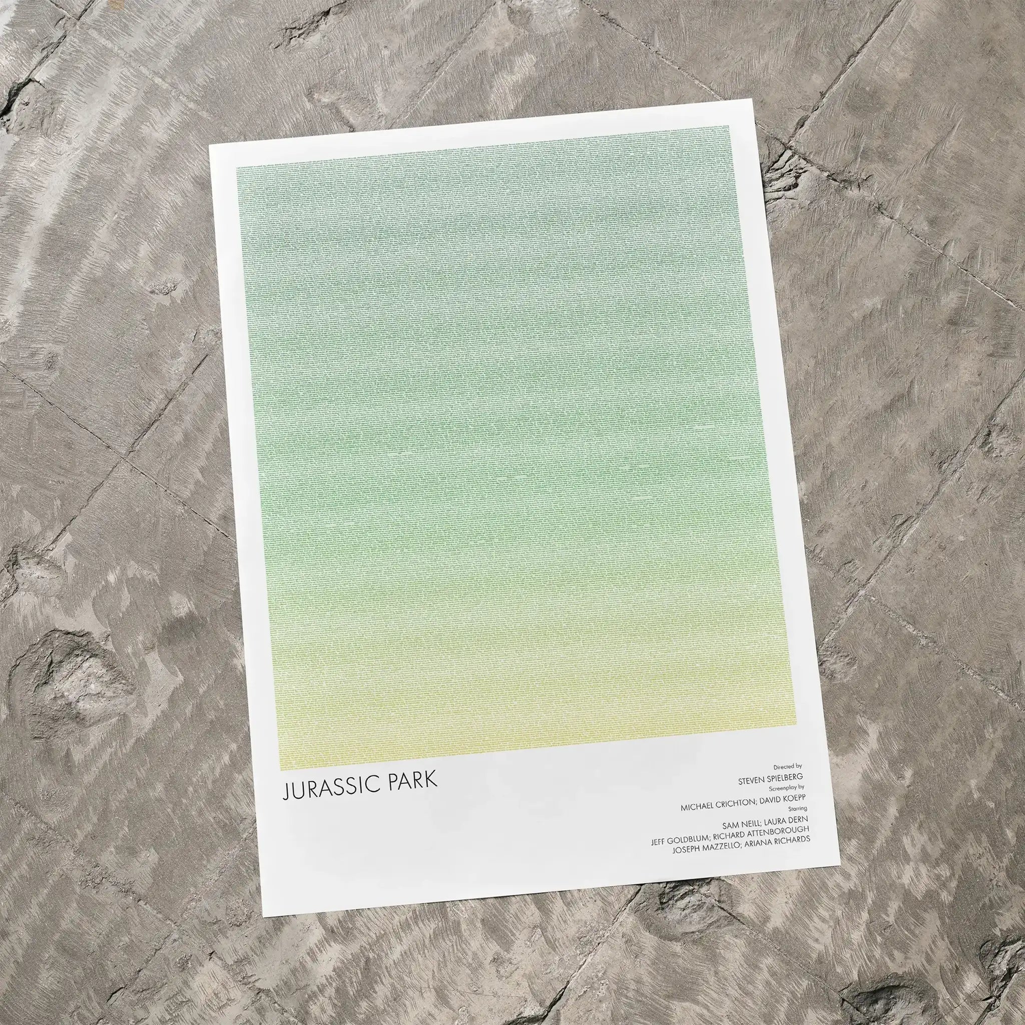 A Jurassic Park movie script poster laid flat on a textured floor surface.