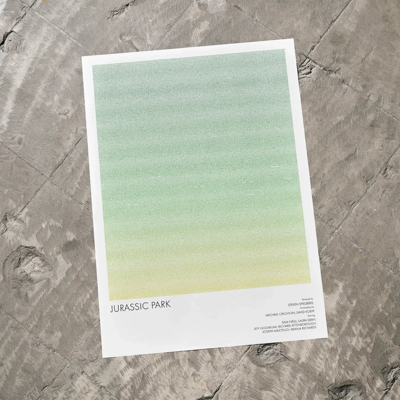 A Jurassic Park movie script poster laid flat on a textured floor surface.