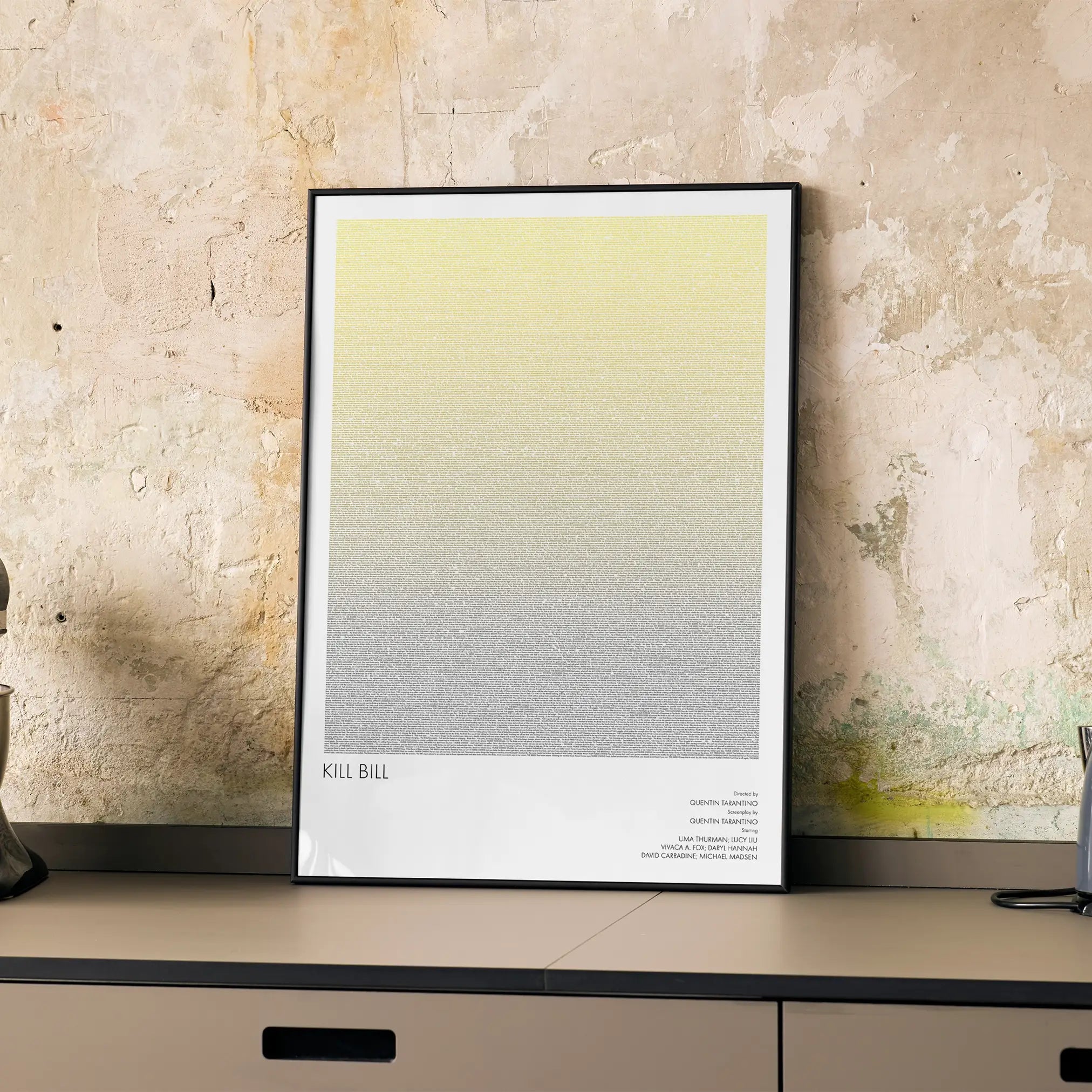 A framed Kill Bill movie script poster displayed on a cabinet in a minimalist interior.