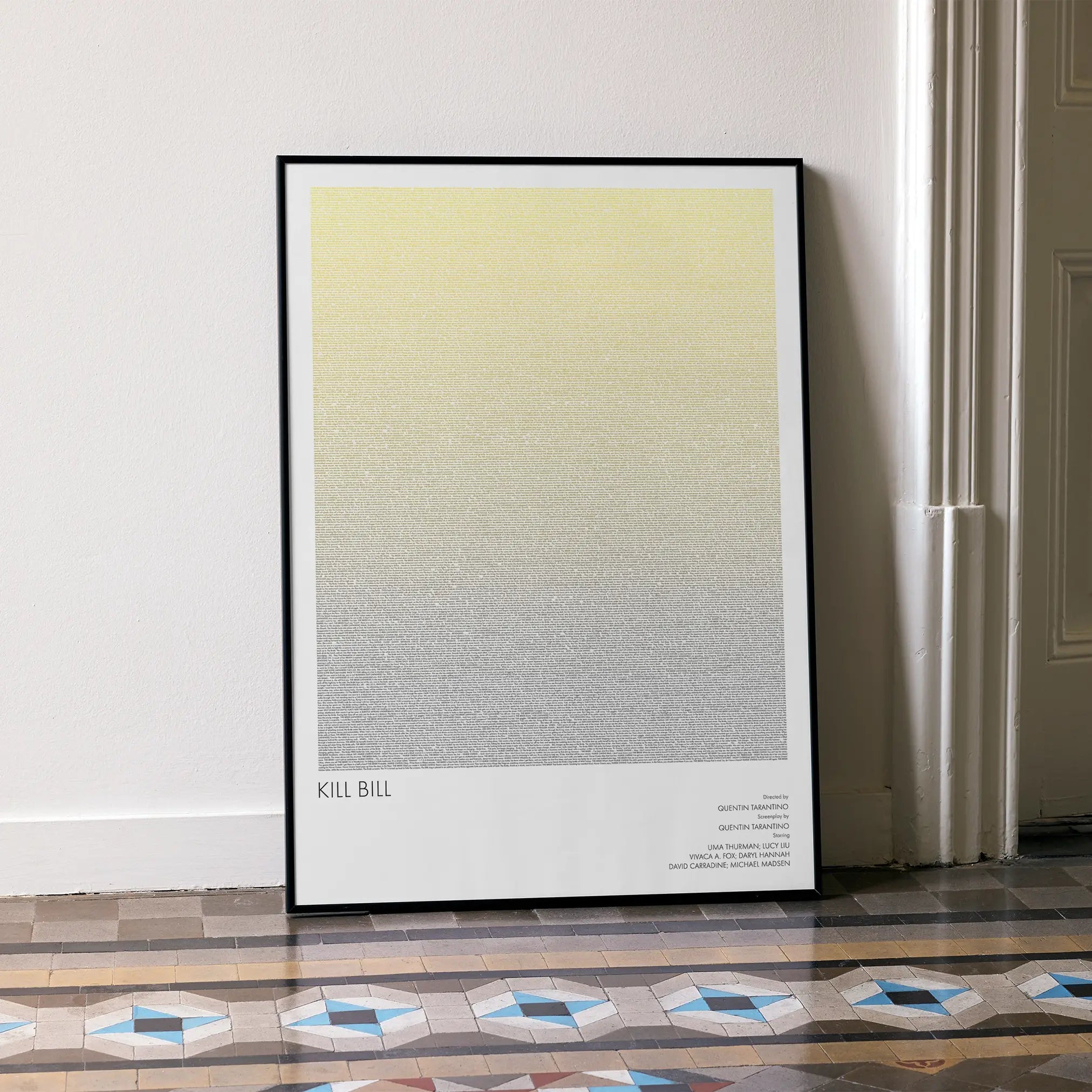 A framed Kill Bill movie script poster leaning against a wall in a minimalist interior.