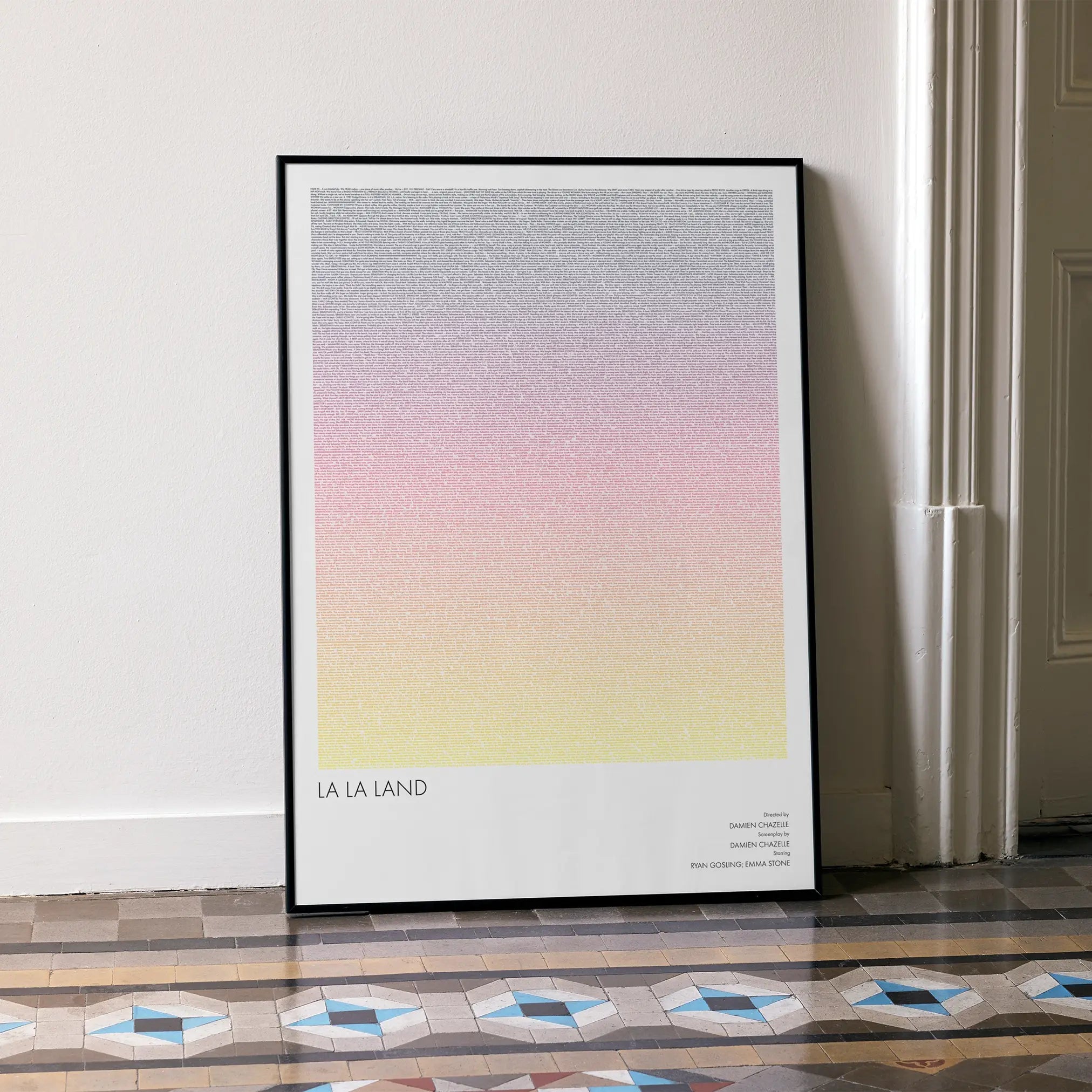 A framed La La Land movie script poster leaning against a wall in a minimalist interior.