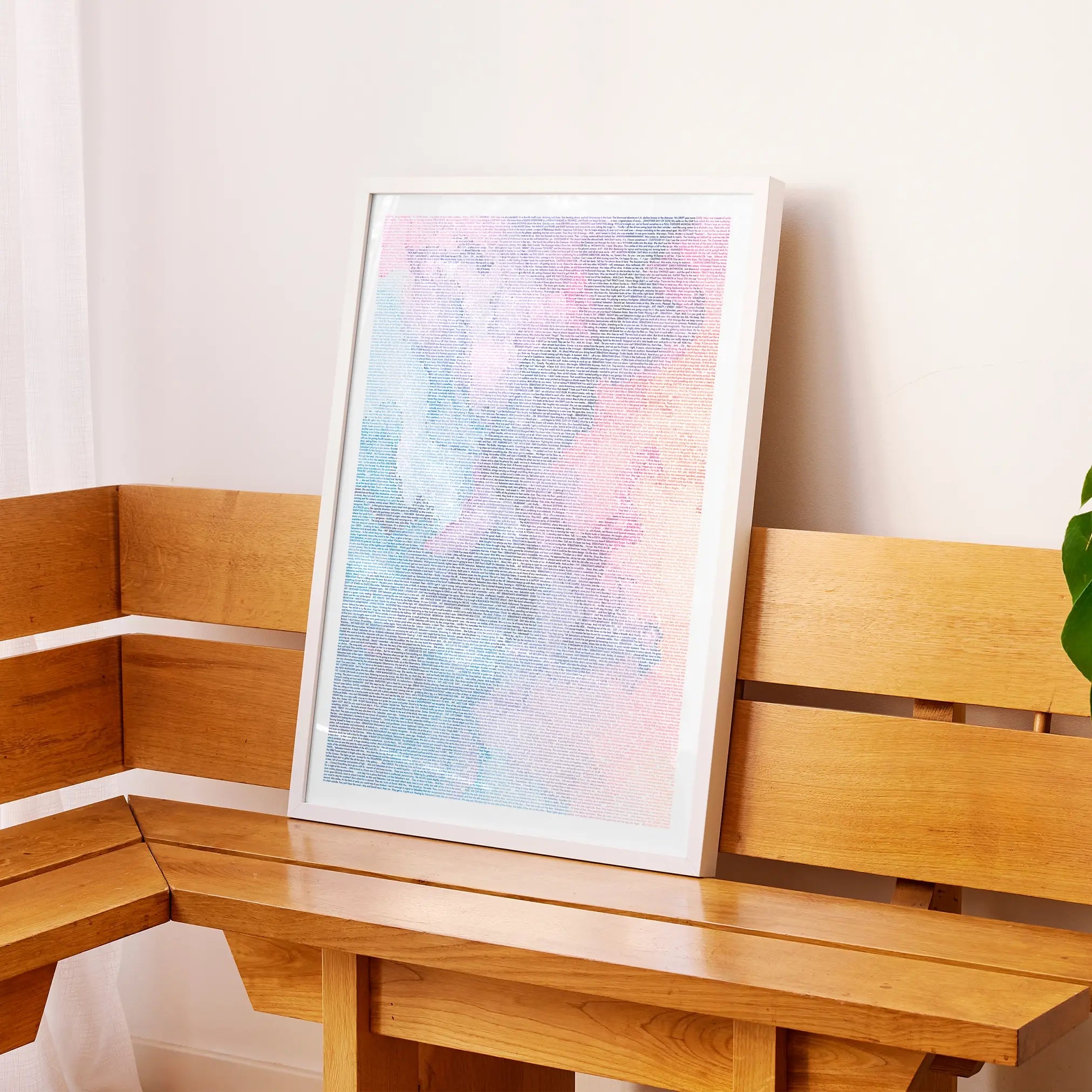 A framed La La Land movie script poster displayed on a wooden bench in a contemporary space.