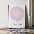 A framed La La Land movie script poster leaning against a wall in a minimalist interior.