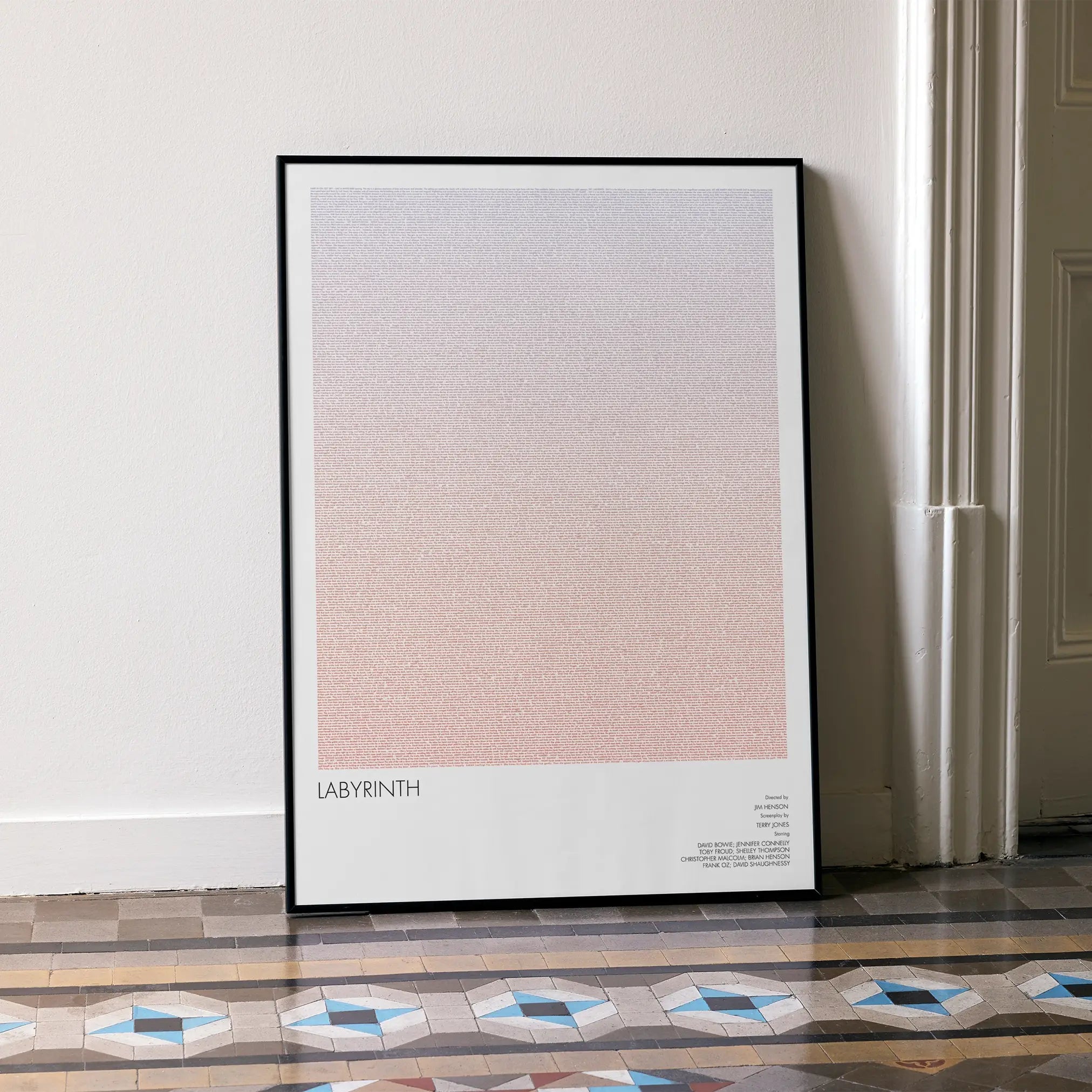 A framed Labyrinth movie script poster leaning against a wall in a minimalist interior.