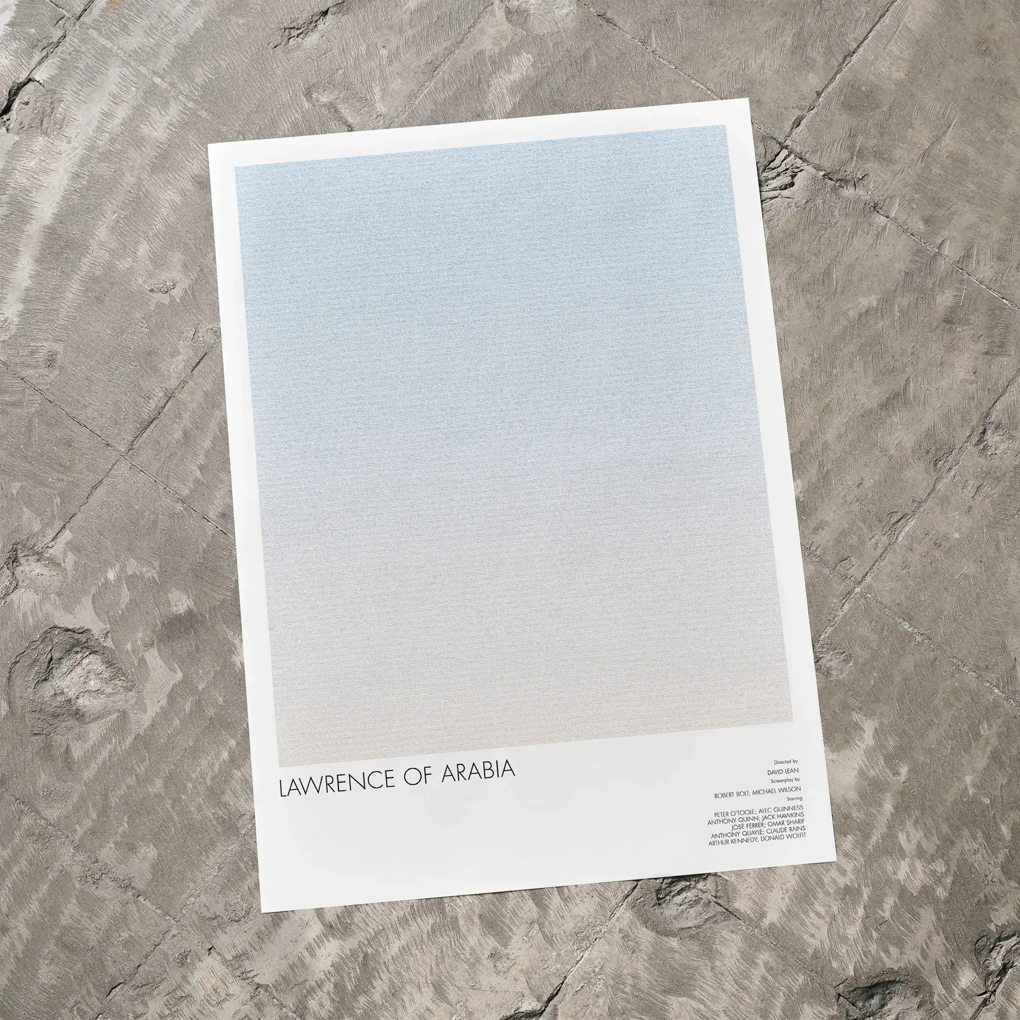 A Lawrence of Arabia movie script poster laid flat on a textured floor surface.