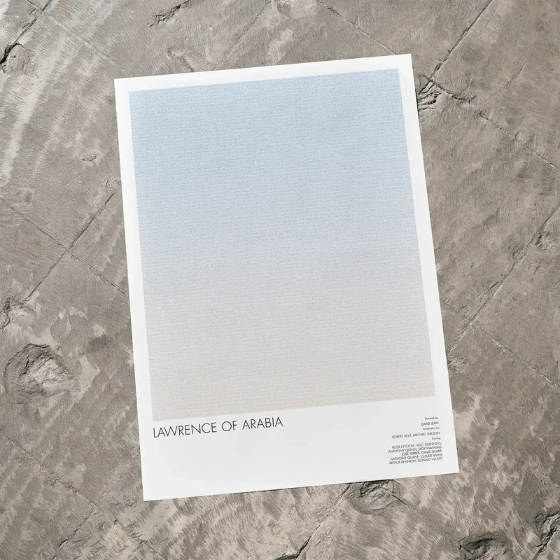 A Lawrence of Arabia movie script poster laid flat on a textured floor surface.