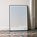 A framed Lawrence of Arabia movie script poster leaning against a wall in a minimalist interior.