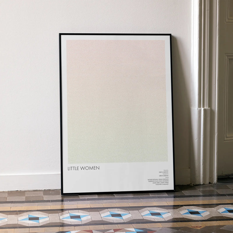 A framed Little Women movie script poster leaning against a wall in a minimalist interior.