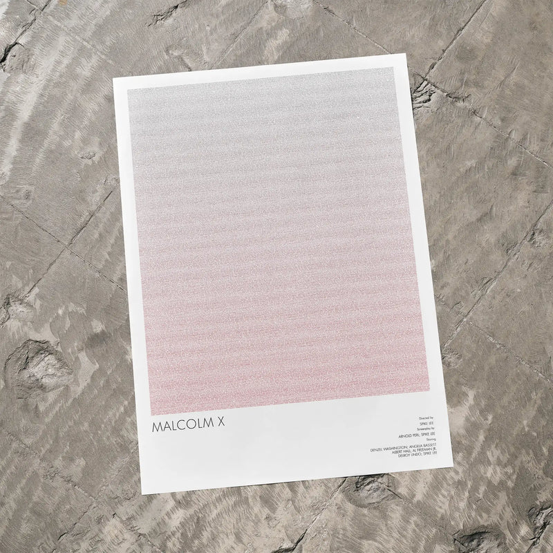 A Malcolm X movie script poster laid flat on a textured floor surface.