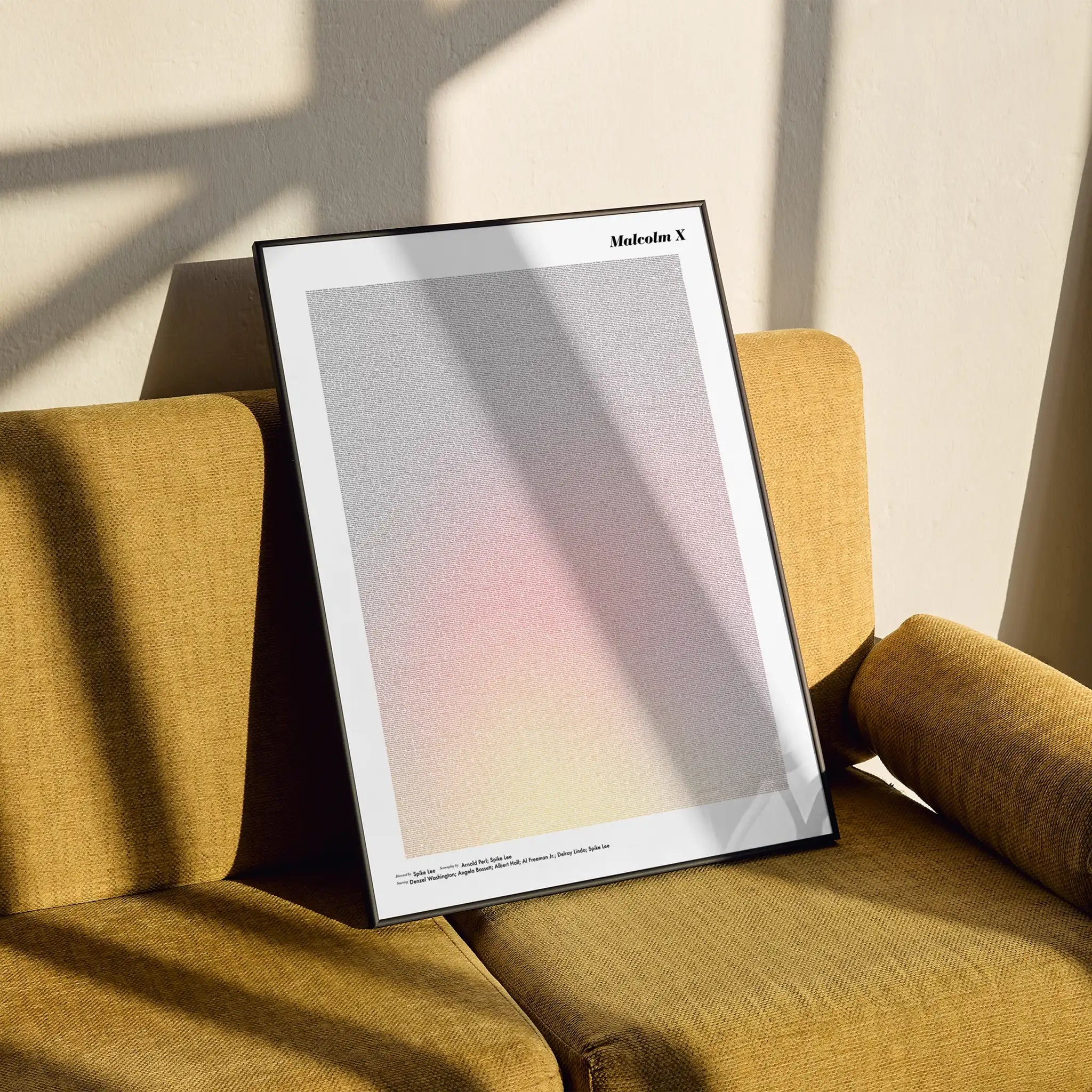 Framed Malcolm X poster on a yellow armchair with soft shadows