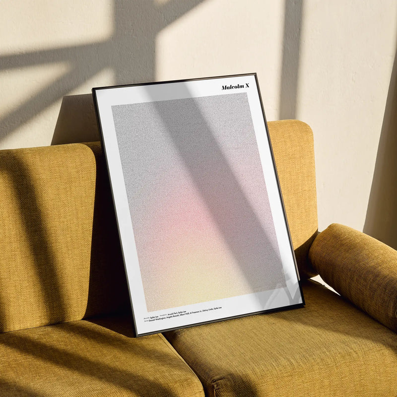 Framed Malcolm X poster on a yellow armchair with soft shadows