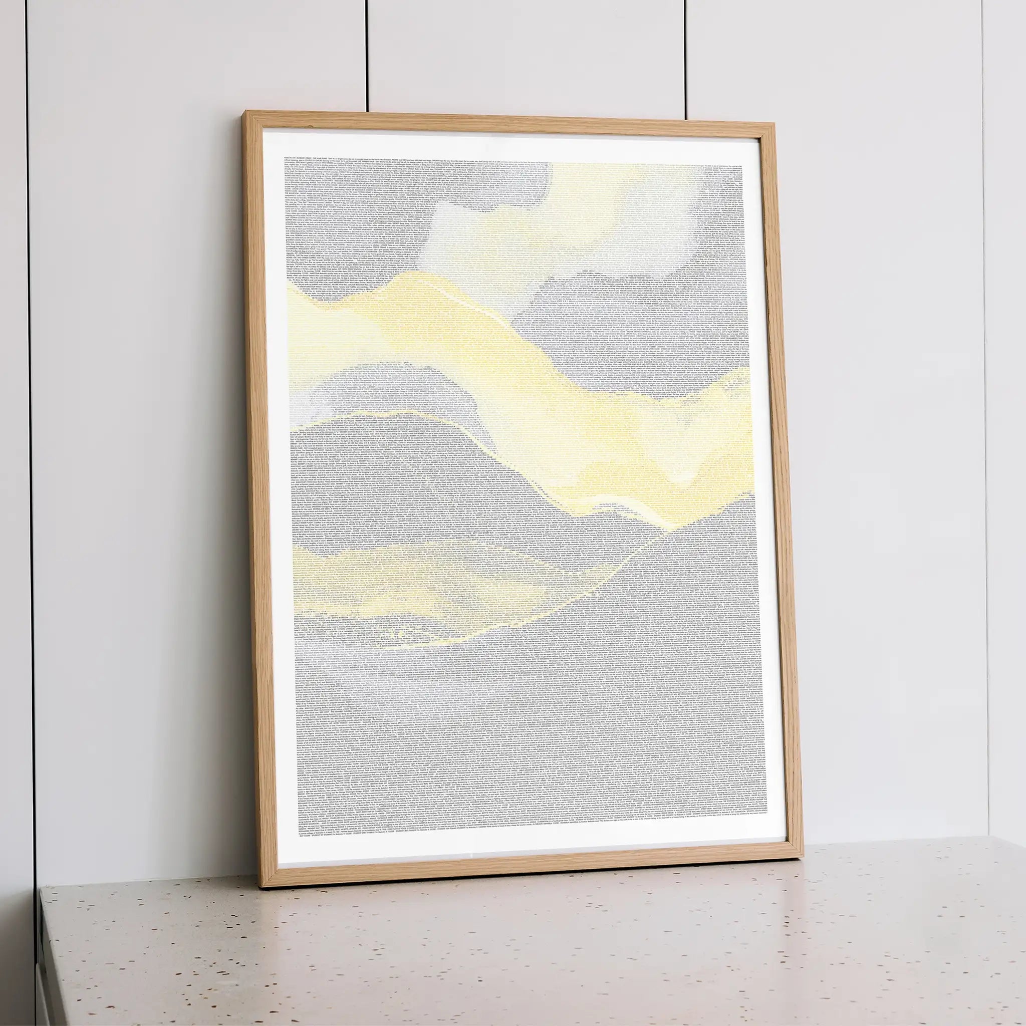 Framed Malcolm X abstract art print with yellow and gray colors on a white wall.