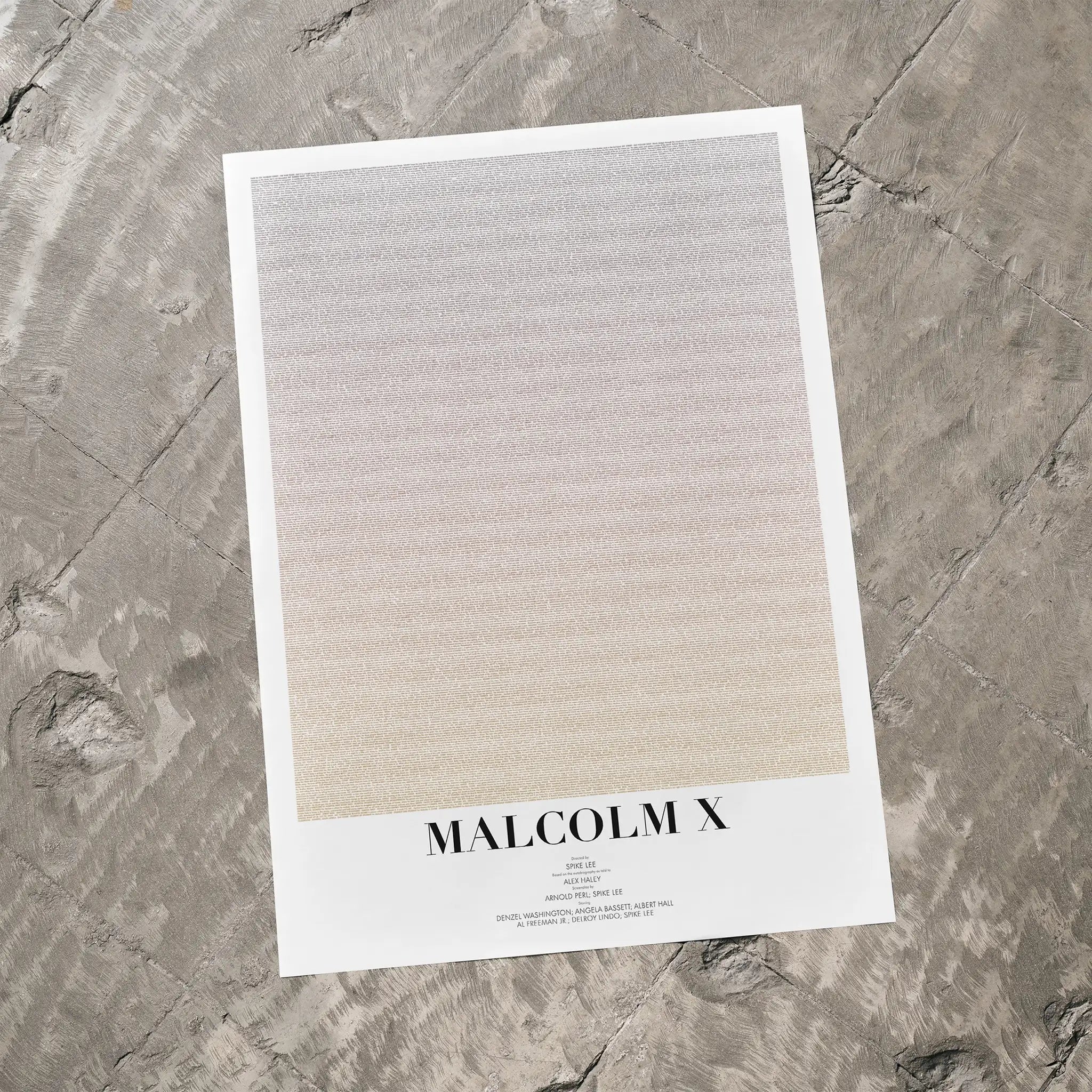 A Malcolm X movie script poster laid flat on a textured floor surface.