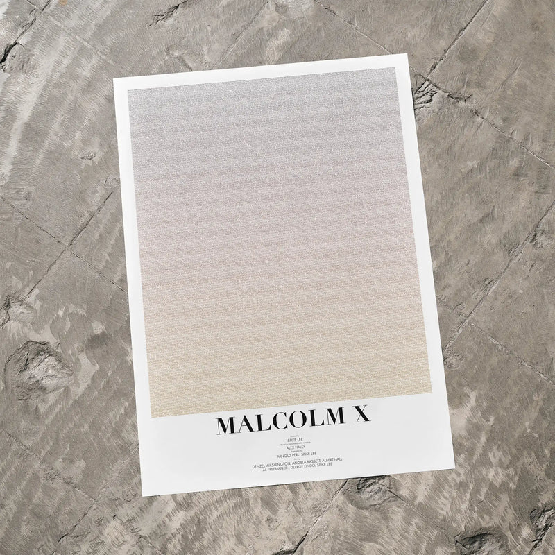 A Malcolm X movie script poster laid flat on a textured floor surface.