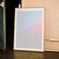 Framed Malcolm X artwork with a gradient leaning against a wooden cabinet.