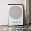 Framed poster with a circular design and 'Malcolm X' text on a white wall.