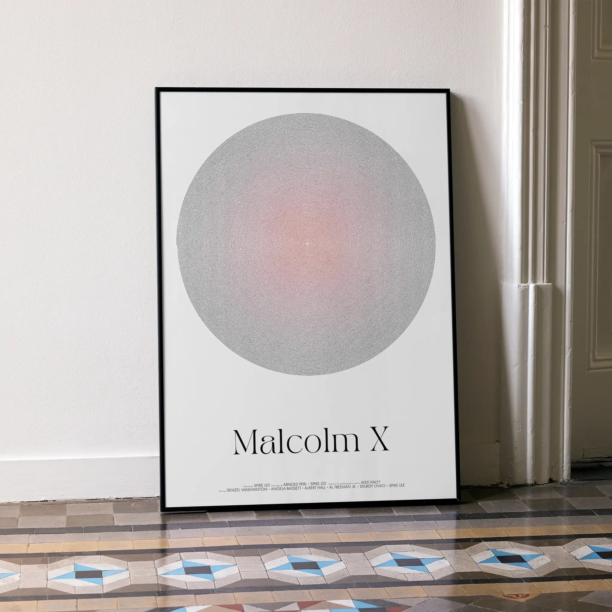 Framed poster with a circular design and 'Malcolm X' text on a white wall.