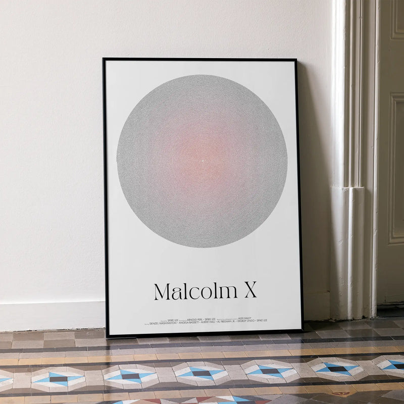 Framed poster with a circular design and 'Malcolm X' text on a white wall.