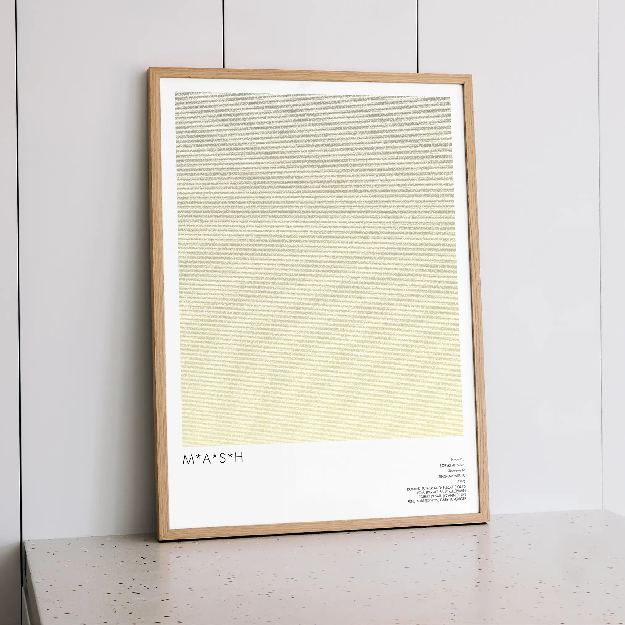 A framed M*A*S*H movie script poster styled within a calm interior space.