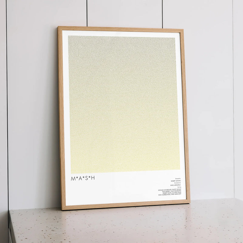 A framed M*A*S*H movie script poster styled within a calm interior space.