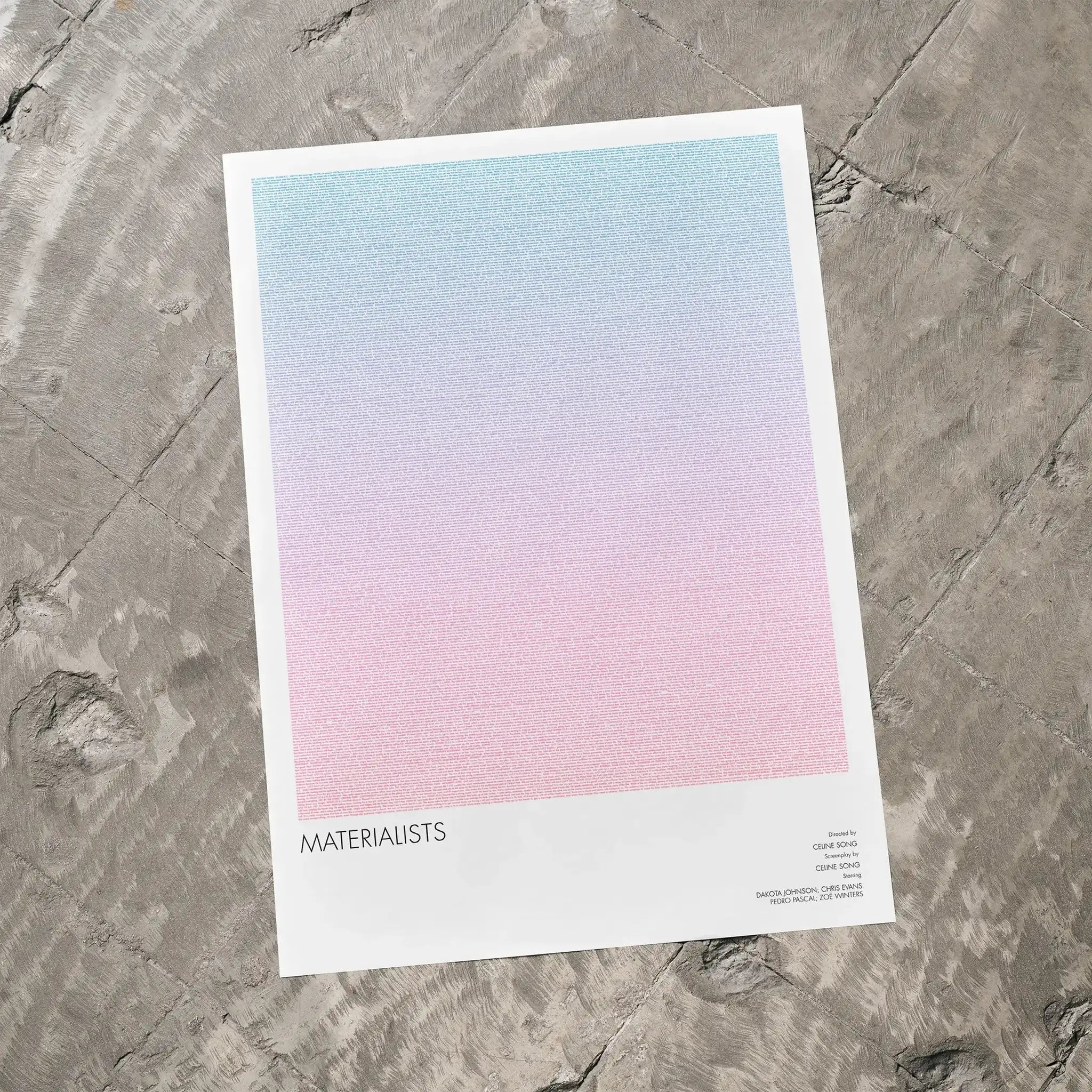 A Materialists movie script poster laid flat on a textured floor surface.