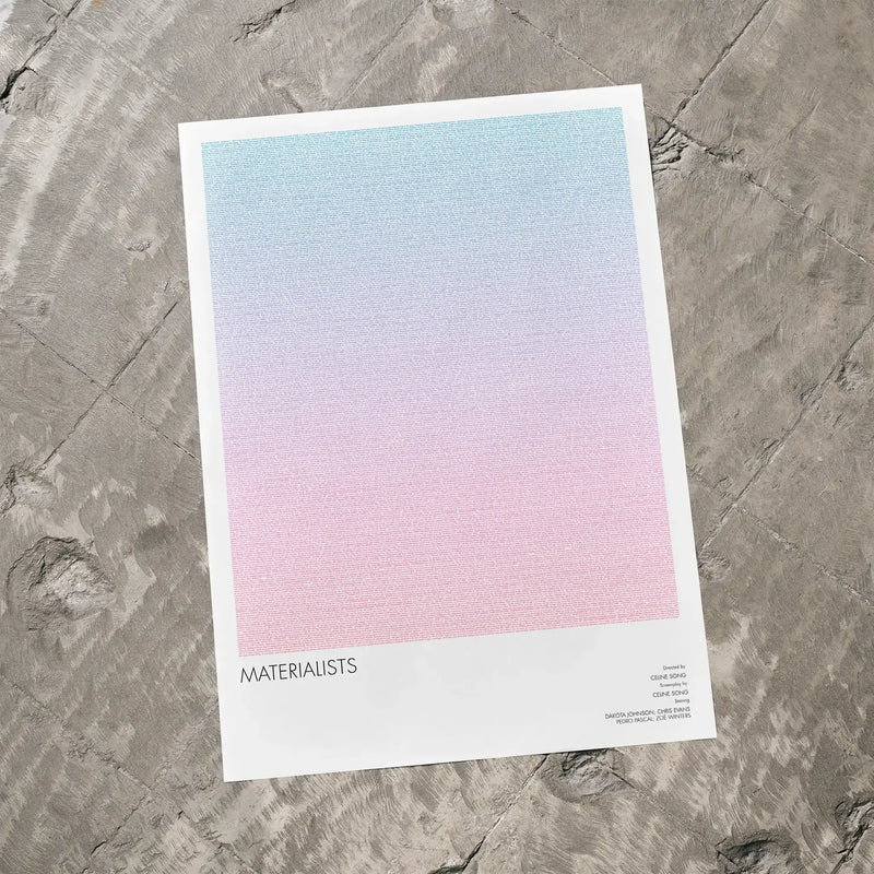 A Materialists movie script poster laid flat on a textured floor surface.