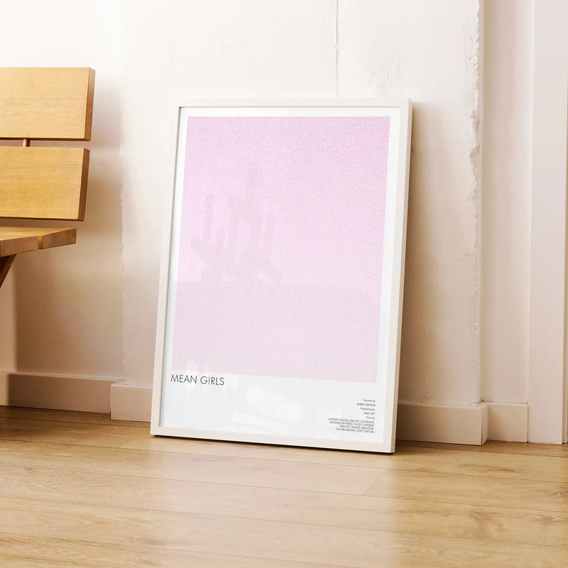 Framed poster titled 'Mean Girls' on a wooden floor against a white wall.