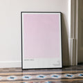 Framed poster with 'Mean Girls' text on a light pink background in a room with patterned floor.