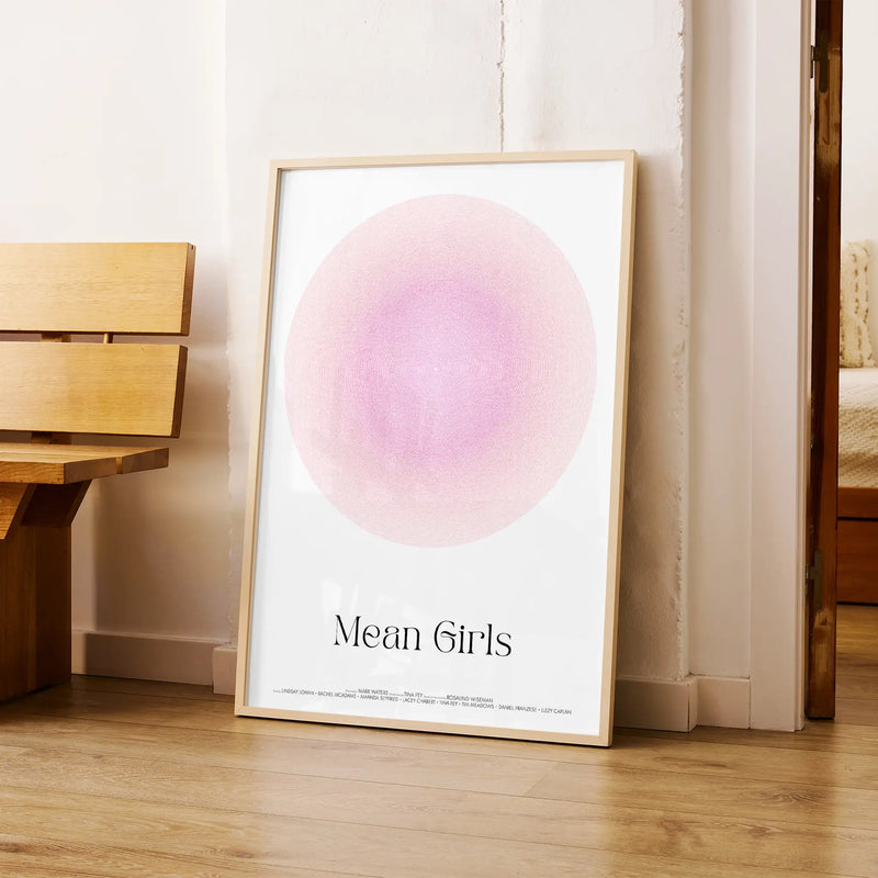 Framed Mean Girls movie poster with a pink circle and 'Mean Girls' text on a wooden floor.