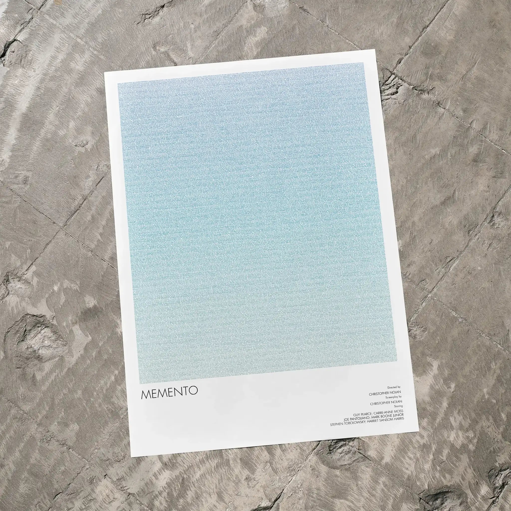 A Memento movie script poster laid flat on a textured floor surface.
