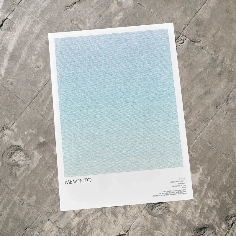 A Memento movie script poster laid flat on a textured floor surface.