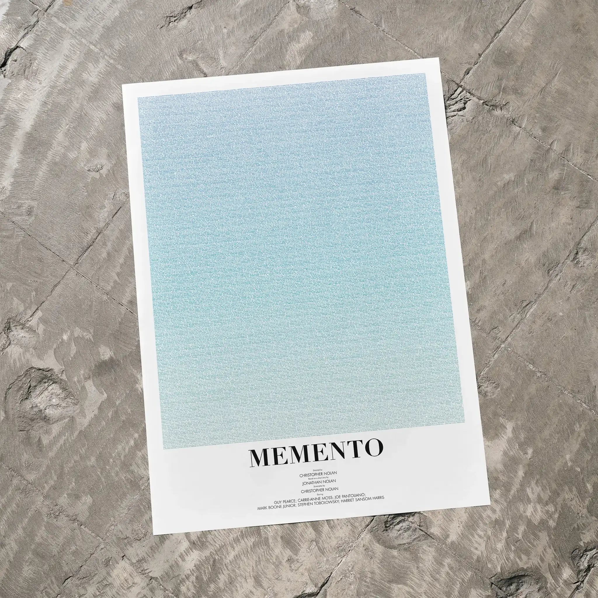 A Memento movie script poster laid flat on a textured floor surface.