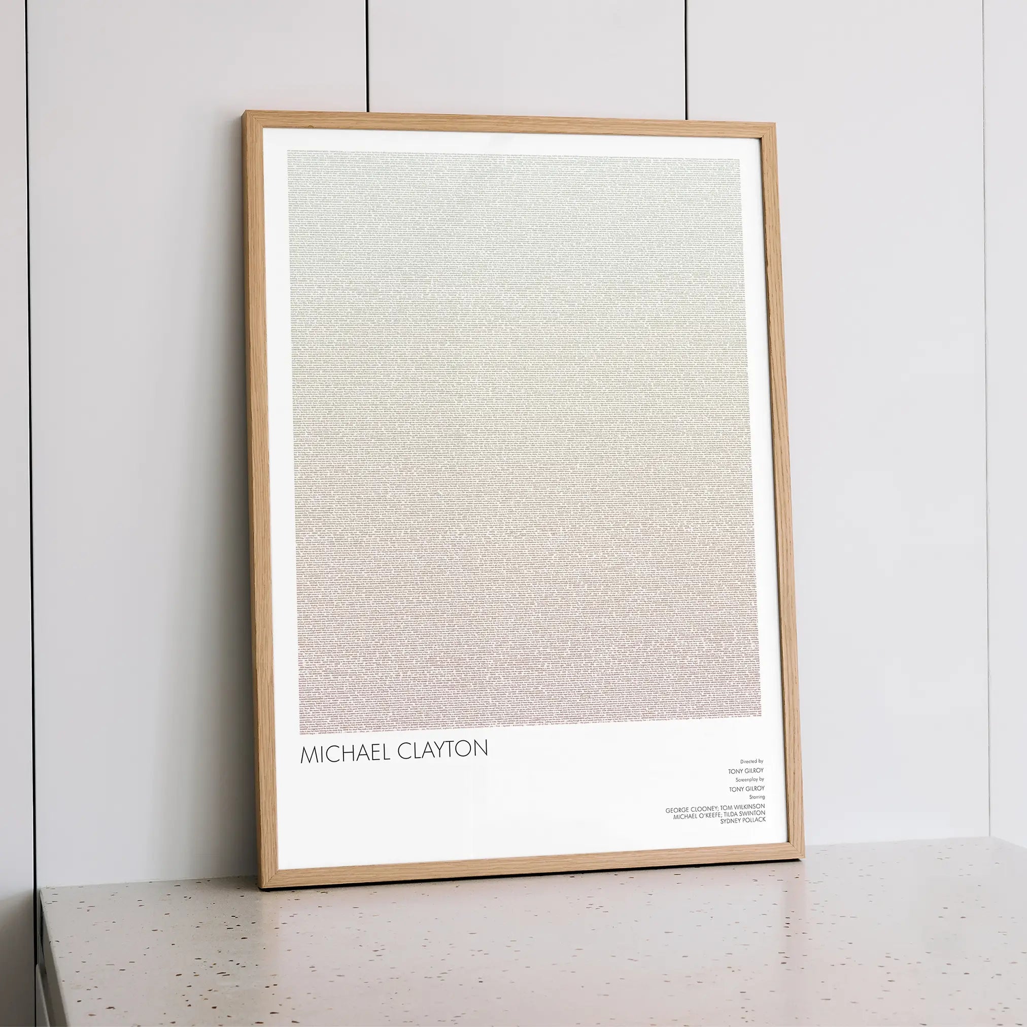 A framed Michael Clayton movie script poster styled within a calm interior space.