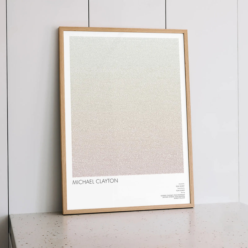 A framed Michael Clayton movie script poster styled within a calm interior space.